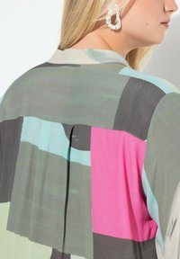 Multifarvet skjorte med abstrakte mønstre i nuancer af grøn, blå, pink og grå. Glat stof, med en læg bagpå og almindelig krave.