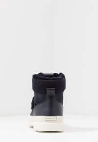 Navy blue winter boot featuring a soft, fleece top and smooth leather heel; white rubber sole, label on the back with "GANT" logo.