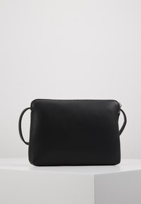 Bolso de mano de cuero negro con un acabado texturizado, forma rectangular y cierre con cremallera. Cuenta con doble asa para un transporte versátil.