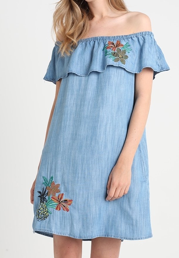 Vaaleansininen farkkukleid, jossa on olkaimeton muotoilu ja röyhelökaulus. Helmaan on kirjottu värikkäitä kukka- ja ananaskuvastoja.