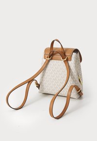 White patterned backpack with brown leather accents, featuring adjustable straps, a top flap closure, and gold-tone hardware.