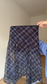 Egy átlátszó fekete szoknya kék-fehér kockás mintával, légies szabással és finom redőkkel a mozgás érdekében.