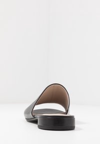 Černé otevřené nazouvací boty s hladkým koženým svrškem, nízkým podpatkem a tvarovanou stélkou pro pohodlí. Minimalistický design bez ozdob.