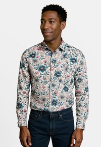 Bloemendruk overhemd met blauwe en roze bloemen op een crèmewitte achtergrond. Lange mouwen, met knopen, gecombineerd met donkere jeans. Glad textuur van de stof.