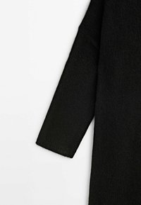 Manteau en laine noir texturé à manches longues sur fond blanc, montrant le bras gauche et une partie du corps.