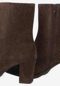 Braune Wildleder-Ankle Boots mit quadratischer Zehenform und Blockabsatz, ausgestattet mit einem seitlichen Reißverschluss für den Verschluss und einer glatten Textur.