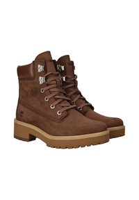 Bruine suede laarzen met een rubberen zool, voorzien van metalen oogjes, veters en een logo-detail. Ronde neus en een gevoerde enkelsteun.