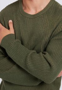 Olivgrüner Strickpullover mit gerippter Textur, rundem Ausschnitt und langen Ärmeln. Verfügt über subtile horizontale Linien und eine taillierte Passform.