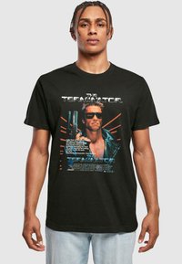 Sort bomulds t-shirt med "The Terminator" grafik, der viser et stiliseret billede af en karakter iført solbriller og fede tekst elementer.