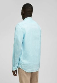 Lichtblauw linnen overhemd met lange mouwen, ronde kraag, knoopmanchetten en een gebogen zoom, gemaakt van een textuurstof. Geschikt voor casual gebruik.