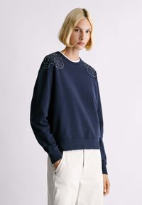 Felpa blu navy con dettagli decorativi sulle spalle, dotata di scollatura a girocollo e polsini a costine, realizzata in morbido cotone.