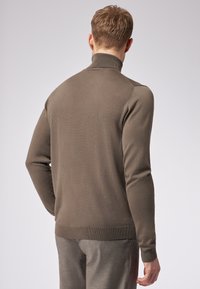 Maglione slim-fit color taupe con colletto alto, polsini e orlo a coste. Presenta un motivo a maglia testurizzata e un tessuto liscio e stretch.