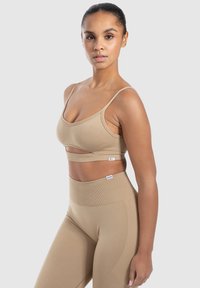 Beige ribbet sportsbh med udskæring, justerbare stropper og matchende højtaljede leggings. Glat tekstur, tætsiddende design.