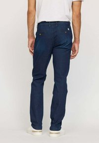 Jeans slim-fit bleu foncé avec une texture lisse. Dotés de deux poches arrière avec des accents de boutons en métal. Style adapté pour un usage décontracté.