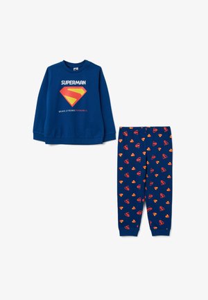 Sweatshirt bleu et pantalon de pyjama assorti avec un motif d'emblème Superman. Le sweatshirt a un col rond, tandis que le pantalon présente un motif de logos.
