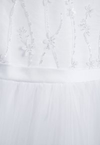 Weißes Kleid mit bestickten Blumenmustern und Pailletten. Das Oberteil besteht aus glattem Stoff, während der mehrlagige Tüllrock für Struktur sorgt.