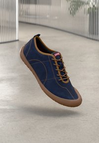 Marineblaue Wildlederschuhe mit braunen Akzenten, runder Zehenpartie, Schnürdesign und flexibler Gummisohle, mit einem roten Logo auf der Zunge.