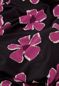 Zwarte stof met grote roze bloemen met witte randen. Zachte textuur met een vloeiende uitstraling, die de bloemenpatronen prominent toont.