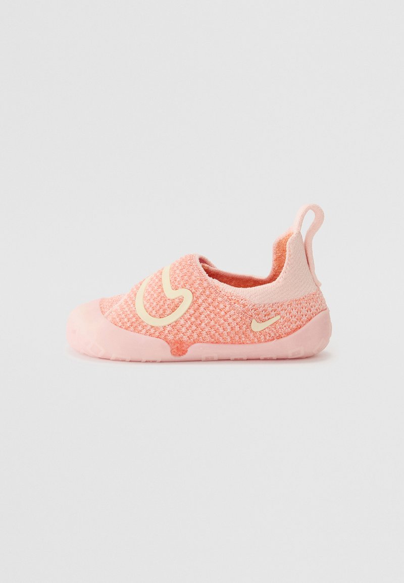Des chaussures slip-on rose clair avec un motif tricoté, dotées d'un bout arrondi et d'un logo swoosh jaune. Matériau souple et flexible avec une semelle en caoutchouc.