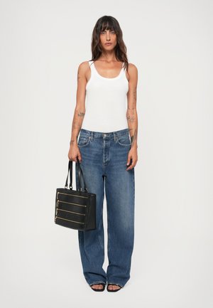 White ribbed tank top, blue wide-leg jeans, black handbag with gold zippers and logo, and black open-toe sandals.