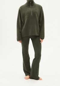 Pullover metà zip in verde oliva in pile abbinato a pantaloni aderenti coordinati; entrambi gli articoli presentano una texture morbida e una vestibilità comoda.