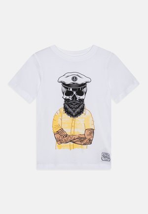 Camiseta de algodón blanca con un gráfico de un cráneo con barba y gorra de capitán, vestido con una camisa amarilla y adornado con tatuajes.