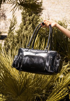 Black leather handbag with dual top handles, multiple zippered pockets, smooth texture, rectangular shape, and glossy finish.