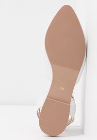 Białe, otwarte sandały na obcasie z gładką cholewką, z beżową, teksturowaną podeszwą. Rozmiar 37 wydrukowany na złoto na dnie.