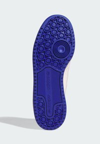 Sól modrej tenisky Adidas s kruhovými vzormi, textúrovaným gripom a logom Adidas, zobrazená na jednofarebnom svetlom pozadí.