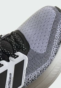 Athletic shoe with a textured grey and black upper, featuring a knitted design, white accents, and black laces for secure fit.
