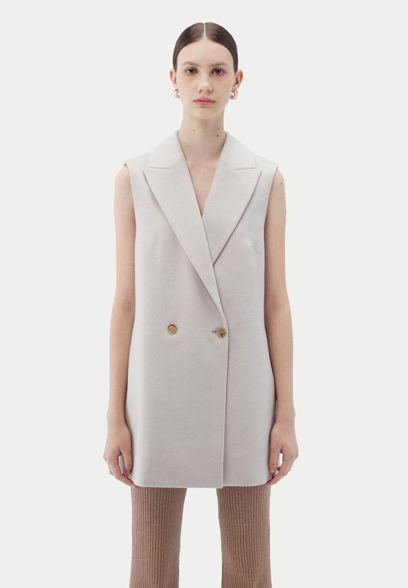 Doppelreihiger ärmelloser Blazer aus hellgrauem Stoff, mit großen goldenen Knöpfen, scharfen Revers und geradem Schnitt.