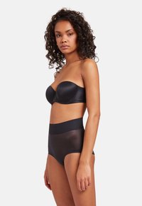 Svart bandeau-bh med en slät satinfinish och höga, genomskinliga svart underkläder med en bred midjeband och sömlös design.