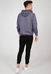 Lila hoodie med en strukturerad yta, med dragsnöre vid huvan och ribbade muddarna, kombinerad med slim fit svarta byxor och vita sneakers.