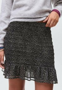 Črna smučena krila z nabranim robom, ki ima subtilen leopardji vzorec v sivih odtenkih, izdelana iz lahkega, teksturiranega materiala.