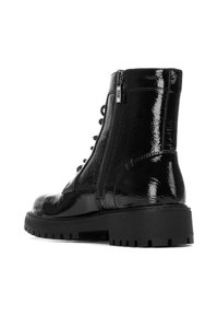 Botín de charol negro con un acabado texturizado, que cuenta con una cremallera lateral, cordones en la parte frontal y una suela de goma gruesa.