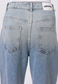 Lyseblå denim jeans med høj talje. Har to baglommer, diskret falmning og et mærke på taljebåndet, der står "URTRN."
