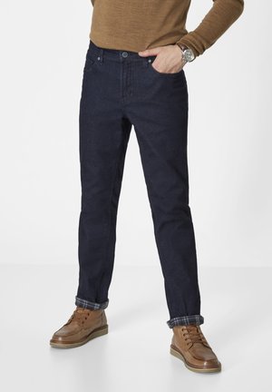 Dark blue denim jeans with a classic fit, five-pocket design, and cuffed hems. Worn with brown leather boots and a brown pullover.