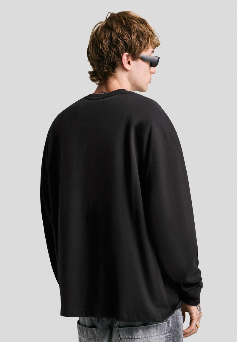 Monki - T-shirt oversize à manches longues et fentes latérales - Noir et blanc rayé