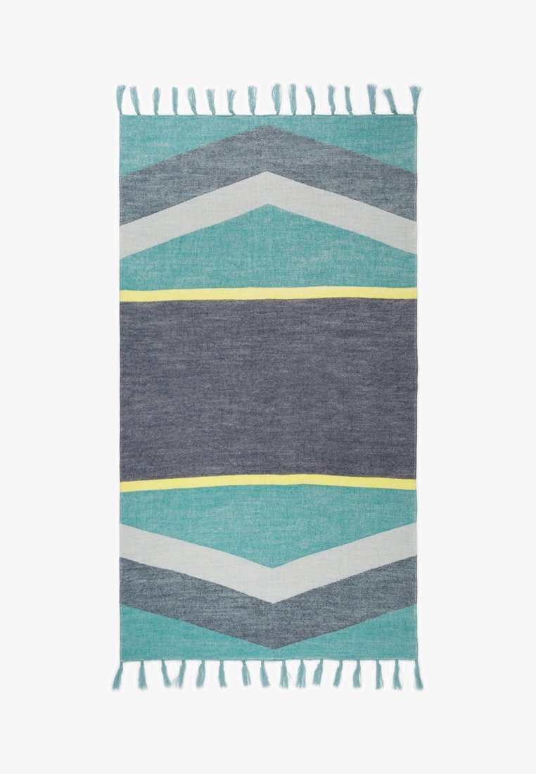 Tapis rectangulaire tissé avec des motifs en chevron turquoise, gris, blanc et jaune, et des franges aux deux bords les plus courts.