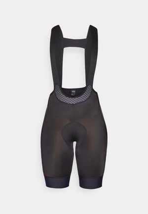 Melni velosipēdu bikses ar regulējamiem siksnām, struktūrētu sietu paneļiem, polsterētu sēdekļa ielikni un atsevišķām kāju piedurknēm.