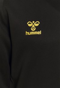 Zwarte sweatshirt met een gladde textuur, voorzien van een geel Hummel-logo en een bijontwerp op de voorkant. Regular fit, ronde halslijn.