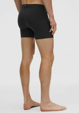 Fekete pamut bokszernadrág, testhezálló kialakítással, varrás nélküli széllel és puha derékkal. Minimalista megjelenés, mintázat nélkül.