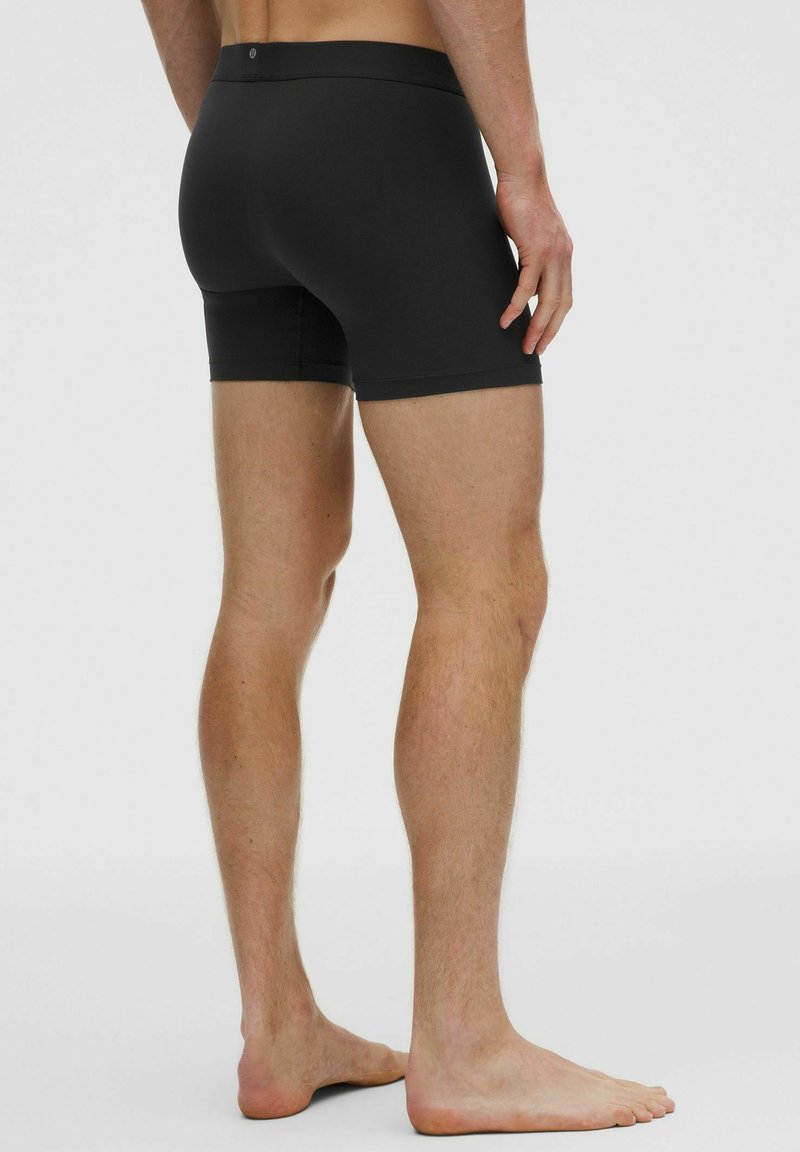 Fekete pamut bokszernadrág, testhezálló kialakítással, varrás nélküli széllel és puha derékkal. Minimalista megjelenés, mintázat nélkül.