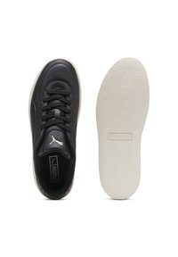 Czarny sneaker Puma widziany z góry obok białej podeszwy z wytłoczonym logo Puma w środku.