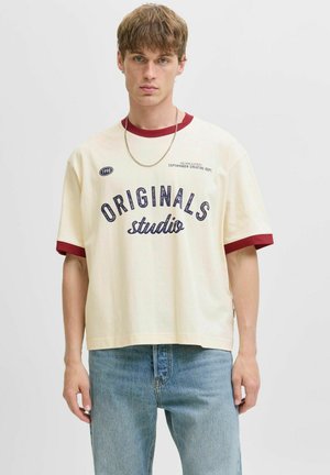 Kratki rukav kremasti T-shirt s maroon rebrastim ovratnikom i manšetama, s natpisom "ORIGINALS studio" u tamnoplavoj boji, ležeran kroj i minimalistički dizajn.