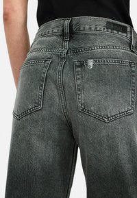 Grijze denim broek met hoge taille, achterzakken en contrasterende stiksels. Kenmerkt zich door een klein metalen logo boven de rechterzak.
