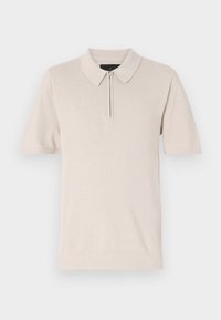 Kortermet polo-skjorte i lys beige, med glidelås i halsen, myk stofftekstur og klassisk kragedesign.