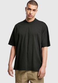 T-shirt noir à manches courtes, de coupe ample, avec un col rond. Fabriqué en coton doux, il présente un design minimaliste avec une texture lisse.