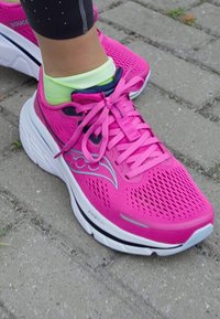 Baskets de course en mesh rose avec un bout arrondi, une semelle blanche et des accents noirs. Elles présentent une ventilation complexe et des lacets en ruban pour un maintien sécurisé.