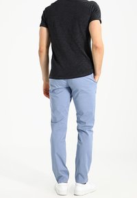 Ljusblå chinos i mjuk bomull, med tapered passform och sidofickor, ihop med en svart tajt t-shirt och vita sneakers.